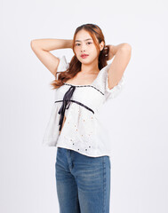 Portrait asian young beautiful woman cheerful long curly wavy hair wearing white puff sleeve blouse with floral embroidery black ribbon blue jeans, look at camera standing posing on white background.