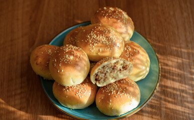 Apetyczne błyszczące domowe bułeczki pszenne posypane sezamem wypchane gotowana kasza z cebulką 