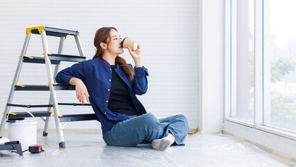 Asian young beautiful woman long curly hair wearing blue shirt jeans sit back on ladder drinking coffee look at window for inspiration while repairing room painting wall house or apartment renovation.