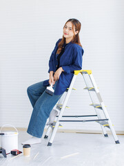 Asian young beautiful woman long curly hair wearing blue shirt jeans posing standing back in ladder...