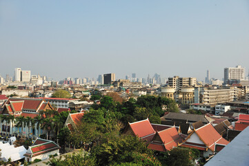 Obraz premium View of buildings with traditional Thai style roof and Bangkok city view at a distance.