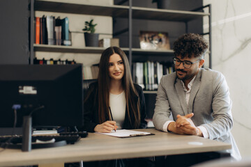 Colleagues Collaborating at Desk in Modern Office Workspace