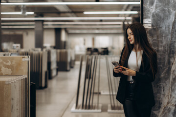 Businesswoman Browsing Smartphone in a Stylish Showroom with Samples