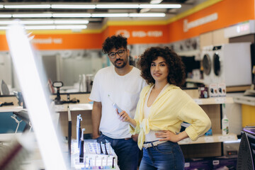 Smiling Customers Shopping for Electronics in a Modern Retail Store. A woman chooses a toothbrush