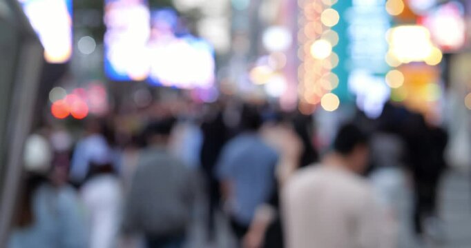 Blurred crowd walking on busy sidewalk near Gangnam Station in evening, colorful building lights and signage create soft bokeh. Typical weekday rush with high pedestrian traffic in vibrant Seoul