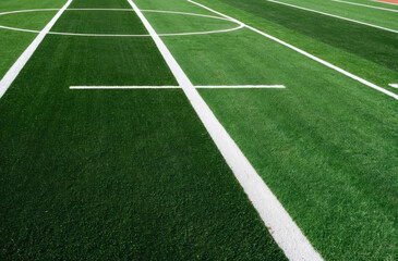 Fototapeta premium close-up view the green grass of a sports field, associated with athletic activities and outdoor recreation.
