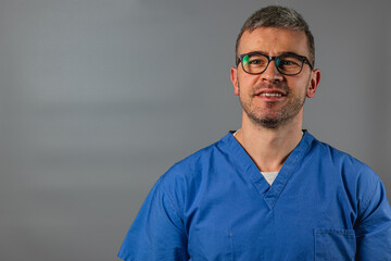 A healthcare professional wearing blue scrubs smiles confidently