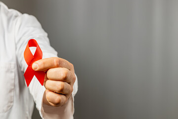 Red ribbon held by a healthcare professional to raise awareness for causes