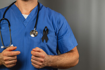 Medical professional wearing blue scrubs and a black ribbon in tribute