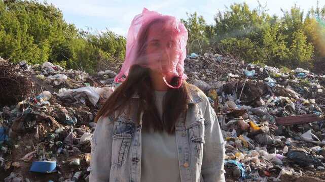 A woman with a pink plastic bag over her head stands before a large trash heap, symbolizing the suffocation caused by plastic pollution.