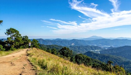 Scenic mountaintop view with a dirt path, green trees, rolling hills, distant mountains, and a vast blue sky