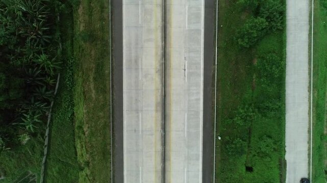 Aerial drone footage of a quiet toll road with a few cars passing by, captured from a high angle.