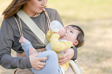 In March, at a sunny forested park in Japan, a Japanese mom in her thirties sits on a bench and...