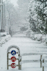 雪が降る遊歩道の車止めの標識縦長