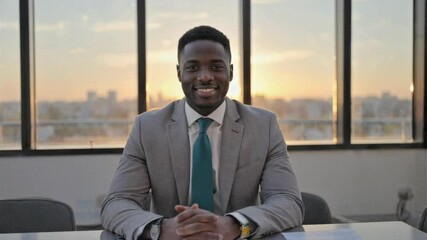 Confident businessman smiling during office sunset meeting