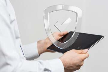 Man uses tablet, digital shield graphic. Data security, online protection, privacy concept.