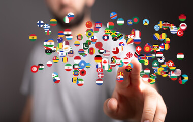 A man interacts with a digital display of world flags, symbolizing global connection and international communication.