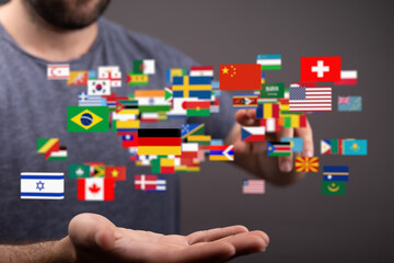 A man interacts with a digital display of world flags, symbolizing global connection and communication.
