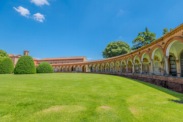 Saint Christopher Church in Charterhouse of Ferrara features a stunning Renaissance porch with elegant arches and columns, alongside a tall bell tower under a clear blue sky in Ferrara city of Italy