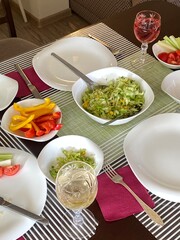 Kitchen table with white plates and fresh vegetables salad. Fresh summer dinner. 