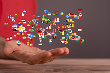 Image of many national flags floating above an open hand, symbolizing global unity and connection.