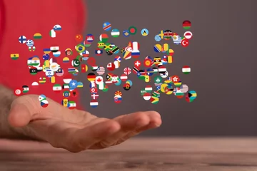 Zelfklevend Fotobehang Image of many national flags floating above an open hand, symbolizing global unity and connection. © vegefox.com