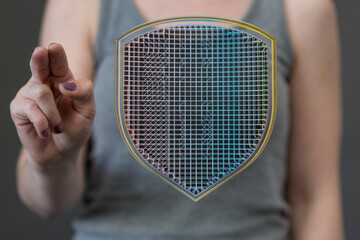 Woman's hand interacts with a digital shield, symbolizing cybersecurity and data protection.