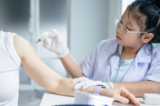 Girl in a doctor's uniform is injecting a syringe into a patient's shoulder