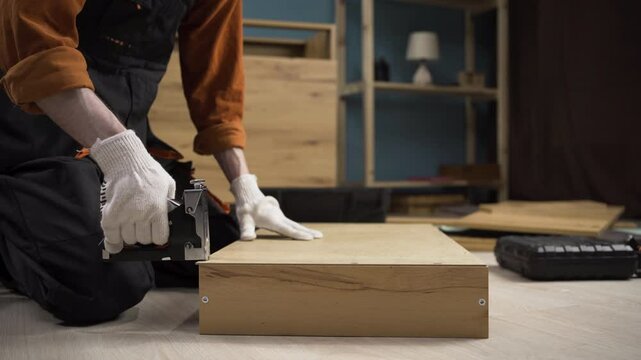 Furniture assembly process, male assembler using stapler to install cabinet part