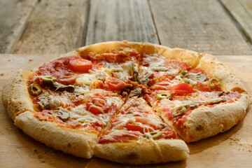 Homemade baked sliced pizza with mushrooms and olives on wooden table