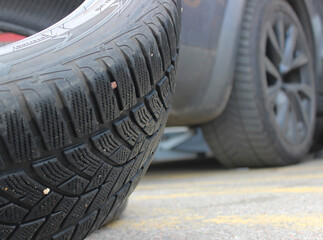  Close up view of punctured tire with blurred car in background at tire service during replacement...