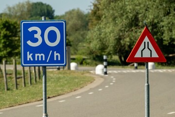 Road narrowing sign and speed limit sign indicate 30 km/h speed restriction