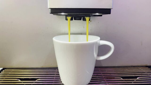 A modern automatic coffee machine is punching hot espresso. Foam and steam are coming out.