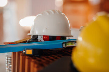 White hard hat, spirit level and bricks resting on construction site