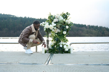 Man igniting candle on bridge decorated with white flowers