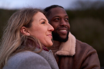 Smiling couple in warm clothing outdoors at dusk