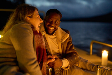 Couple enjoying champagne on pier with candles at night