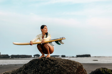 Surfer preparing for the waves at a rocky beach on a clear day, showcasing skill and passion for...