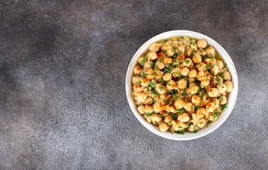 Lebanese warm chickpeas with parsley, spices and olive oil on grey background, top view. Copy space. Balila or msabaha.