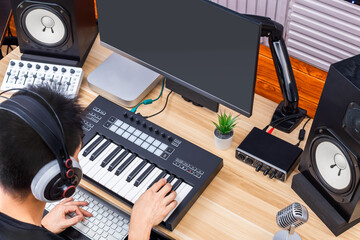 top view of asian man playing midi keyboard in home studio. music production or online music education concept 