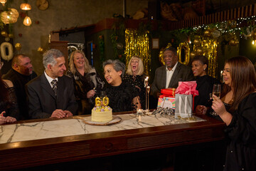 People with birthday cake at 60th birthday party at nightclub