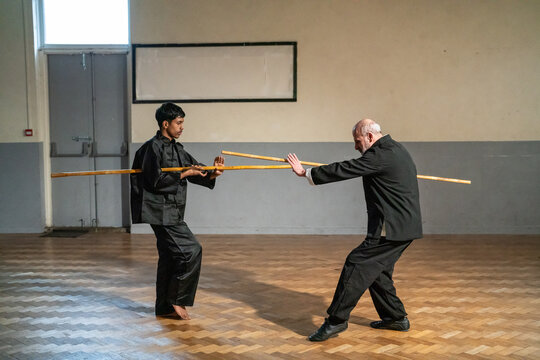 Man with wooden stick undergoing Kung Fu Black Belt test