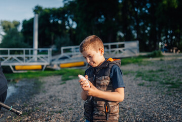 Young fisherman holding freshly caught fish by riverbank