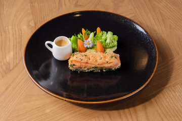 Grilled Salmon with Vegetables and Sauce on Black Plate
