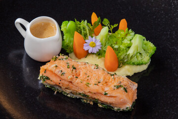 Grilled Salmon with Vegetables and Sauce on Black Plate