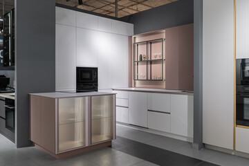 stylish modern built-in kitchen with upper and lower cabinets, drawers, shelves. kitchen facades are white and peach in color. Large, bright kitchen unit. Built-in kitchen appliances. white countertop