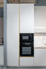 design of large built-in kitchen is white with gold elements, marble countertop, golden faucet and...