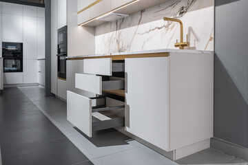 stylish modern built-in kitchen with upper and lower cabinets, drawers, shelves. kitchen facades are white and peach in color. Large, bright kitchen unit. Built-in kitchen appliances. white countertop