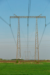 A tall power line tower is in the middle of a field