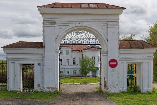 A white building with a red roof and a red sign on the gate